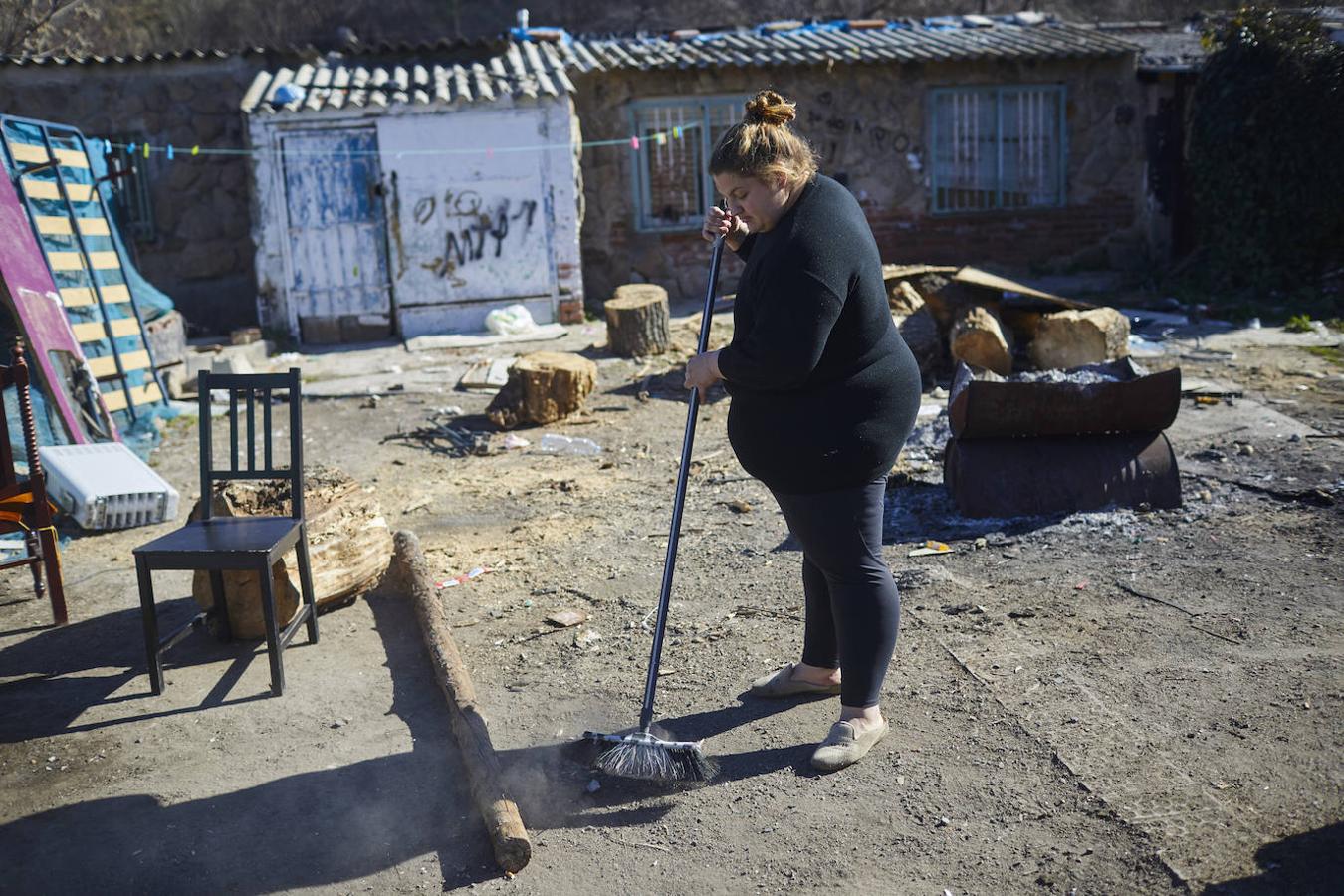 Una mujer barre los restos de basura delante de su casa. 