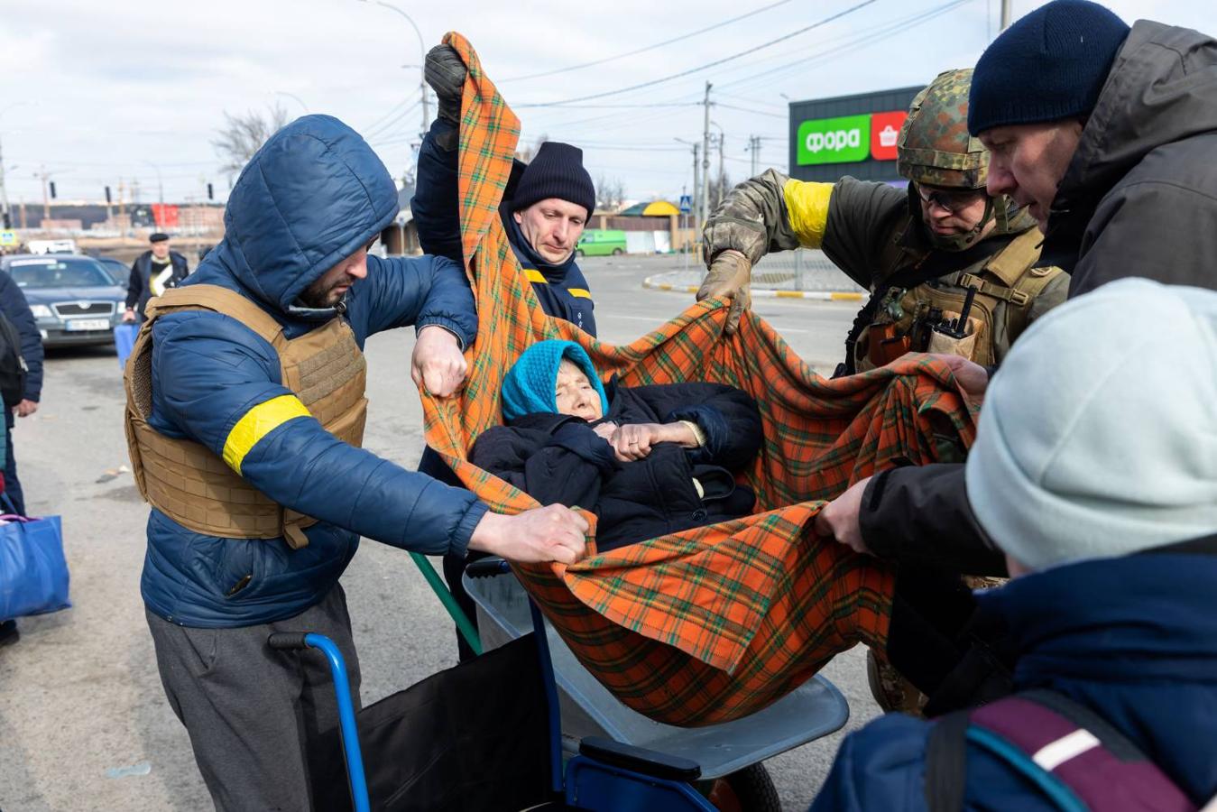 Militares y voluntarios ayudan a evacuar a una anciana en un corredor humanitario. 