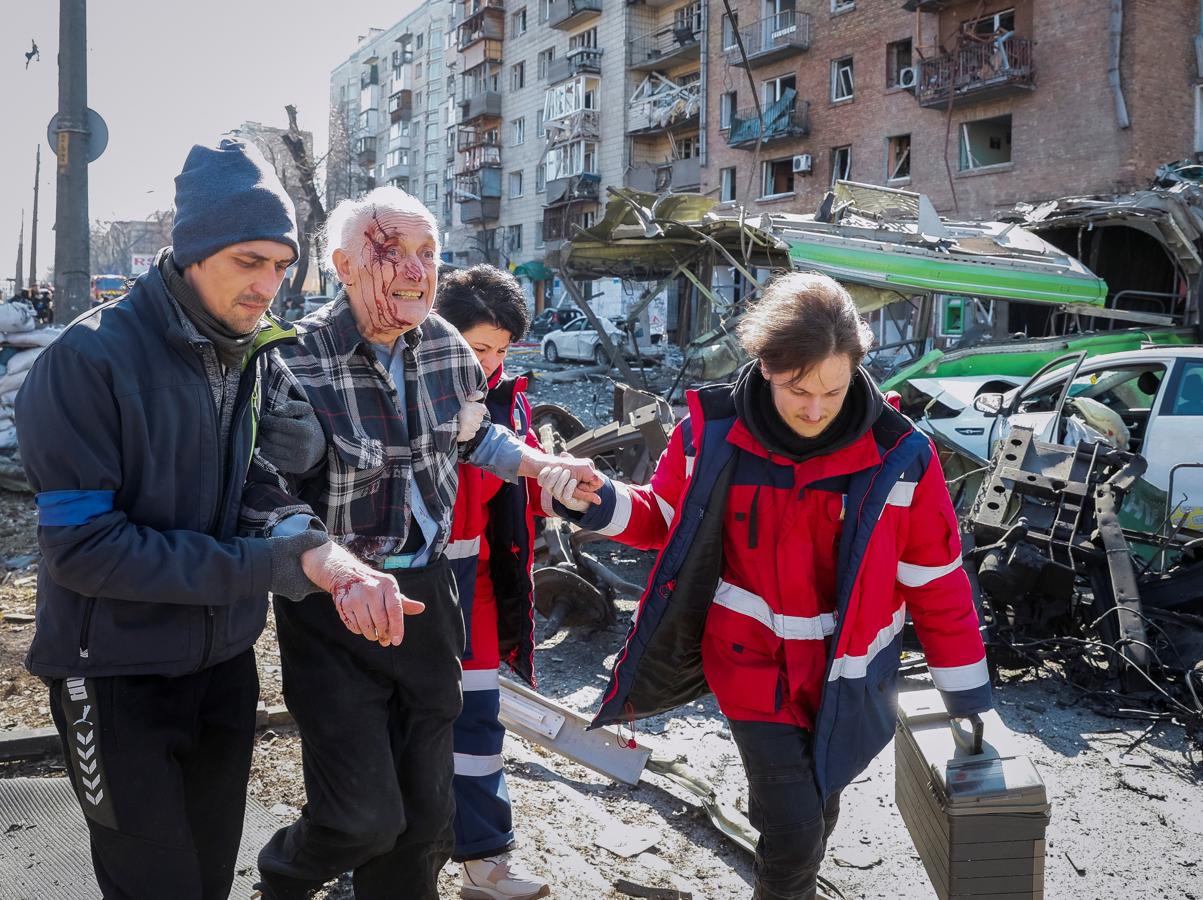 Personas y médicos ayudan a un residente herido de una casa destruida por los bombardeos en Kiev. 