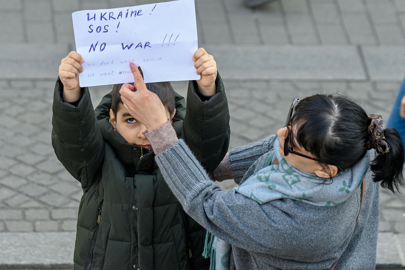 Un niño sostiene un cartel en contra de la guerra. 