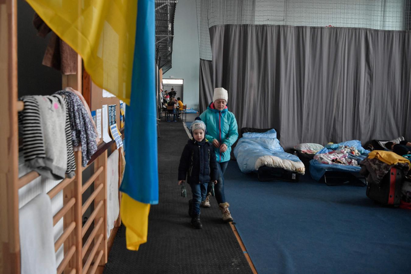 Una mujer y un niño caminan en un centro de acogida de refugiados improvisado en un gimnasio de Przemysl, Polonia. 