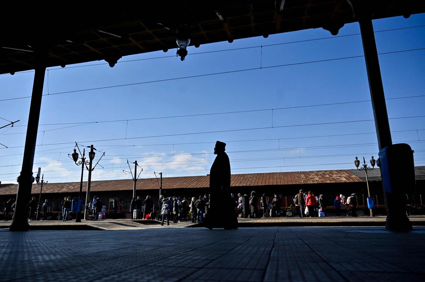 Un sacerdote camina mientras los evacuados ucranianos esperan para abordar un tren que se dirige a Bucarest. 