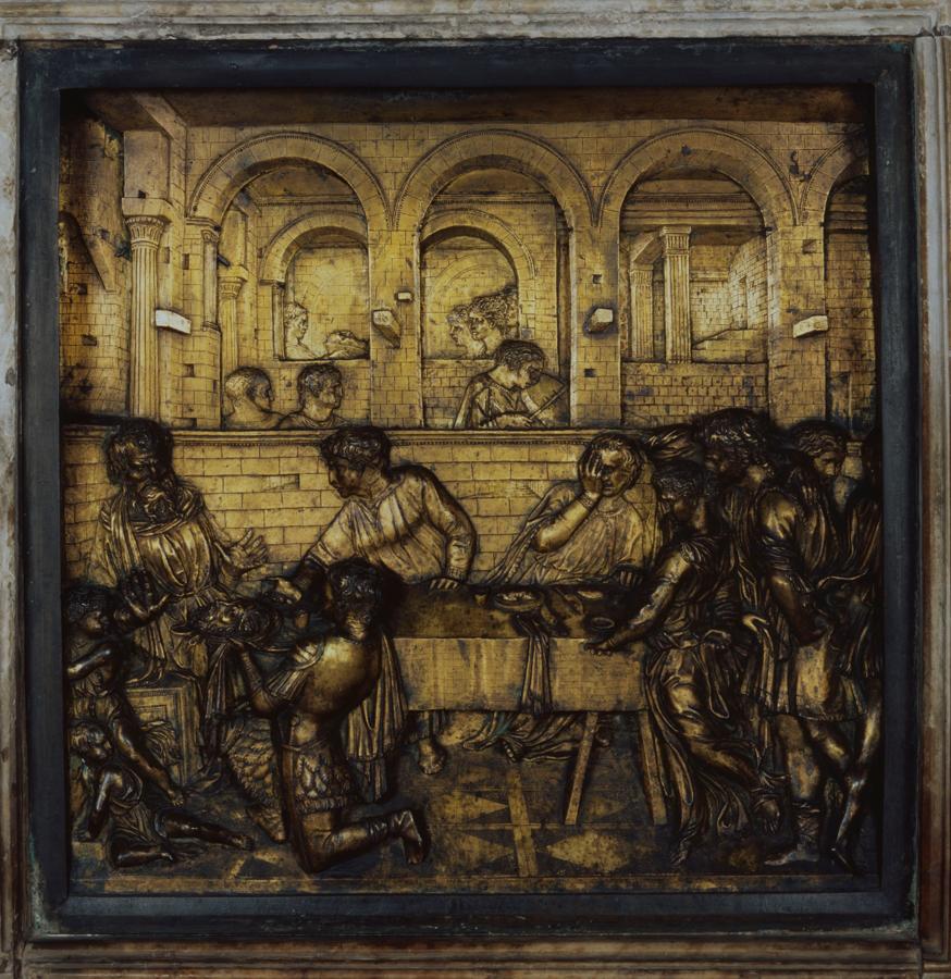 'El festín de Herodes' antes de su restauración. Este panel de bronce dorado de 60 cm por 60 cm es una de las obras más significativas del artista florentino. Conservado en la pila bautismal del Baptisterio de Siena, muestra múltiples escenas de la presentación de la cabeza de Juan el Bautista al rey Herodes en una bandeja de oro por parte de un soldado arrodillado.