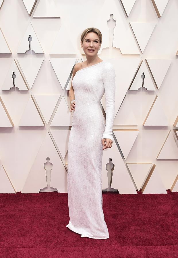 Renée Zellweger en 2020 - Los vestidos más icónicos de los Oscar. Rindió una oda al minimalismo gracias a este modelo de Armani Privé que presentaba un sencillo corte en el que el escote asimétrico se hacía con el protagonismo y en donde las lentejuelas caían con delicadeza y se ajustaban a su figura. Lo combinó con unos stilettos de Jimmy Choo en color blanco con los que remató el look.