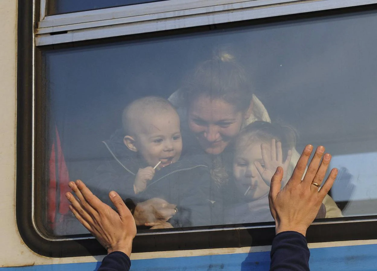 Familias divididas. Una mujer con dos niños se despide de sus seres queridos desde un tren camino de Polonia, el país al que se han dirigido ya dos millones de refugiados