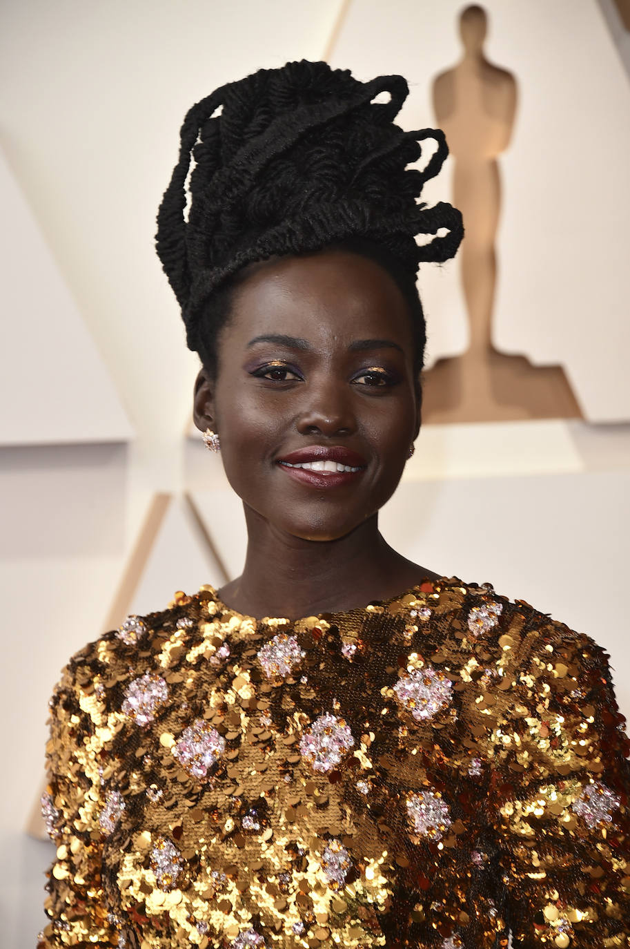 Lupita Nyong'o con uno de los peinados más originales de la alfombra roja de los Oscar 2022. La actriz ha lucido un recogido XXL con trenzas y un bonito maquillaje, con sombras metalizadas y labios rojos con acabado gloss.