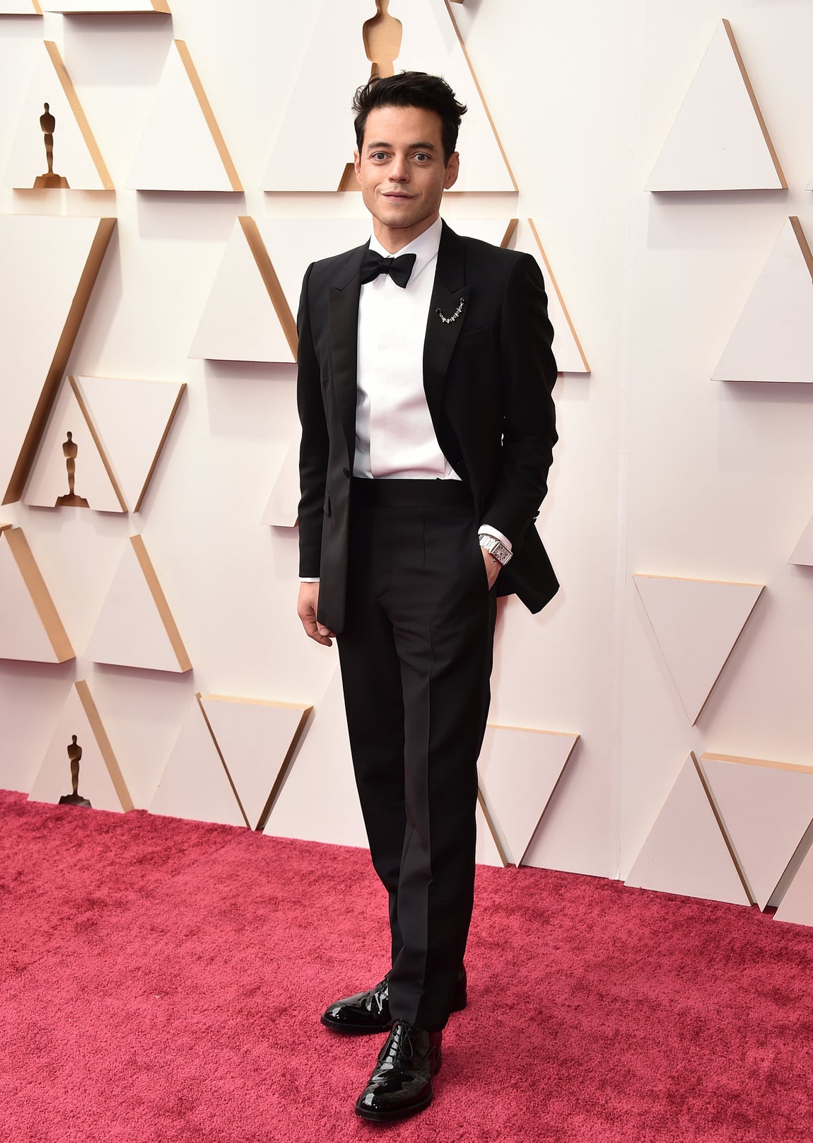 Rami Malek- Los mejor vestidos de los Oscar 2022. Muy correcto, el actor optó por un esmoquin impoluto de Prada que adornó con broche de Cartier de lo más sofisticado de la noche.