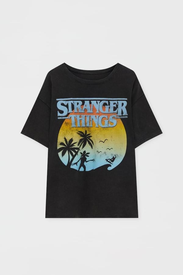 Pull&amp;Bear - Prendas inspiradas en Stranger Things. Camiseta negra de algodón con cuello redondo y print central de estilo vintage, de Pull &amp; Bear. Precio: 15,99 €.