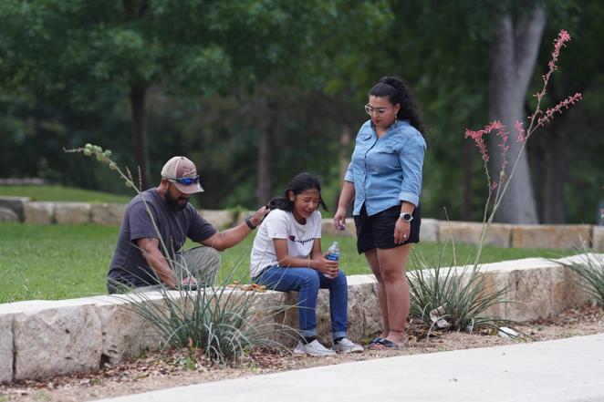 Una niña llora, consolada por dos adultos, fuera del Centro Cívico Willie de Leon donde se brindará un acto de duelo en Uvalde. 