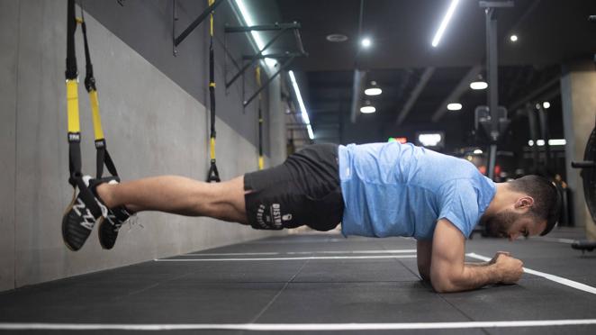 Plancha. Con este ejercicio trabajamos el 'core'. Para ello nos ponemos en posición de decúbito prono y metemos los empeines por las cinchas del TRX. Nos apoyamos sobre los antebrazos y elevamos la cadera, extendemos las rodillas y mantenemos la posición isométrica apretando glúteo y abdomen.