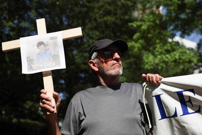 Un hombre sostiene la fotografía de uno de los niños muertos en la escuela de Uvalde durante una concentración de protesta celebrada a las puertas de la Convención Nacional del Rifle.