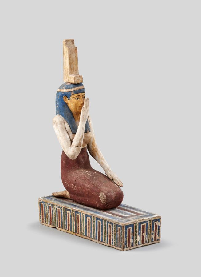 Isis, en duelo. La figura de madera estucada y policromada del periodo ptolemaico (332-30 a.C.) representa a Isis sentada de rodillas y con el brazo derecho levantado y ante el rostro, en actitud de duelo, como signo de silencio y respeto por la muerte de Osiris. Procede del museo de Hildesheim