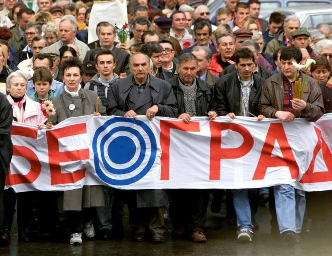 24 de abril de 1999. Varios ciudadanos de Belgrado llevan velas, flores y una pancarta con el nombre de la ciudad y un objetivo dibujado mientras caminan hacia el edificio de la televisión serbia que había sido bombardeado el 23 de abril por misiles de la OTAN, matando a doce personas e hiriendo a otras dieciocho. 