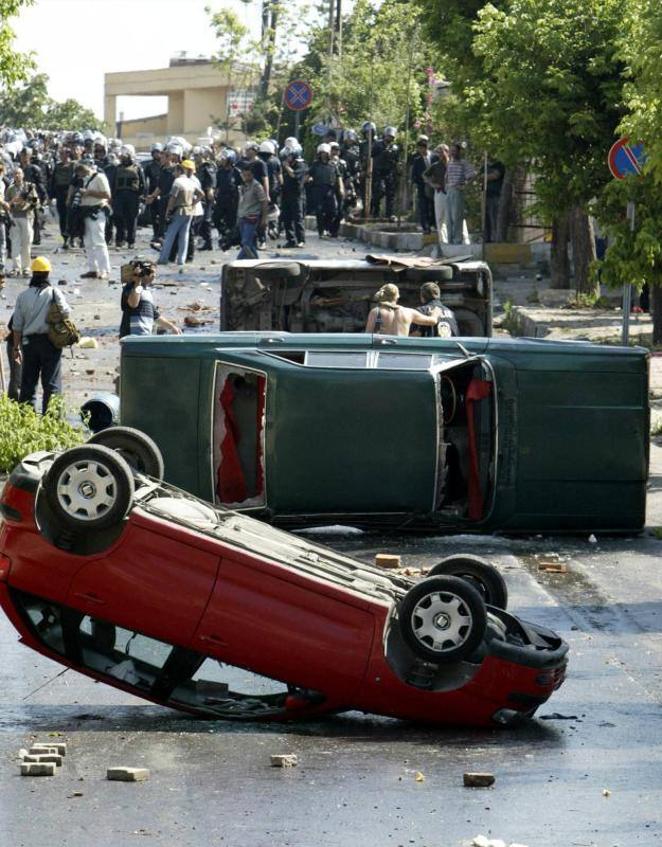 28 de junio de 2004. Algunos coches fueron volcados después de una manifestación de militantes turcos que intentaban irrumpir en el área de seguridad de la cumbre de la OTAN en Estambul. En protesta por la cumbre de la OTAN, los manifestantes arrojaron cócteles molotov y piedras a la policía y las fuerzas de seguridad respondieron con cañones de agua, gases lacrimógenos y porras. Al menos 15 personas resultaron heridas, incluidos cinco policías, y unas 2.000 intentaron abrirse camino a través de un control de carretera hacia el llamado «valle de la OTAN», un complejo de salas de conferencias y hoteles encerrados con barreras de hormigón, donde se realizaba la reunión.. 