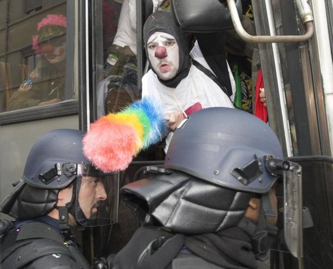 3 de abril de 2009. Un miembro del llamado «ejército de payasos» limpia el casco de un policía antidisturbios francés con un plumero, después de que la policía detuviera el autobús que transportaba a unos 50 payasos del ejército divertido de ir al centro de Estrasburgo para protestar contra dos días Cumbre de la OTAN.. 