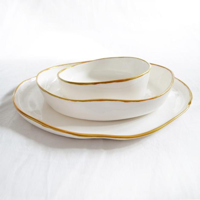 Vajilla cerámica Tonocby Miyaya en Pepita de Oliva. «Buscamos, diseñamos y construimos pensando en la eternidad», bajo esta máxima nace Pepita de Oliva, este taller de carpintería y tienda de decoración ubicada en la ciudad de A Coruña. Abrió sus puertas en 2013 y se ha convertido en toda una referencia, posicionándose como uno de esos negocios locales que apuestan por la artesanía, la autenticidad y el 'made in Spain'. El Proyecto Pepita de Oliva arranca en 2013 y ya se ha convertido en toda una referencia, posicionándose como uno de esos negocios locales que apuestan por la artesanía y la autenticidad. Entre sus propuestas, esta fabulosa vajilla fabricada a mano en España en cerámica brillante. Su diseño presenta un elegante cerco dorado en el borde y un diseño irregular inspirado en las curvas topográficas. Precio: 400€