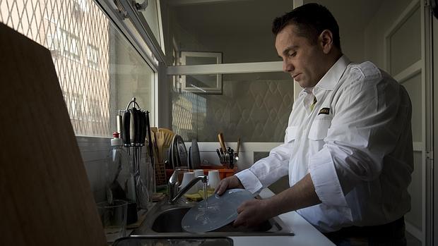 Un hombre friega los platos en su vivienda