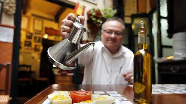 Un camarero derrama aceite sobre un pan con tomate