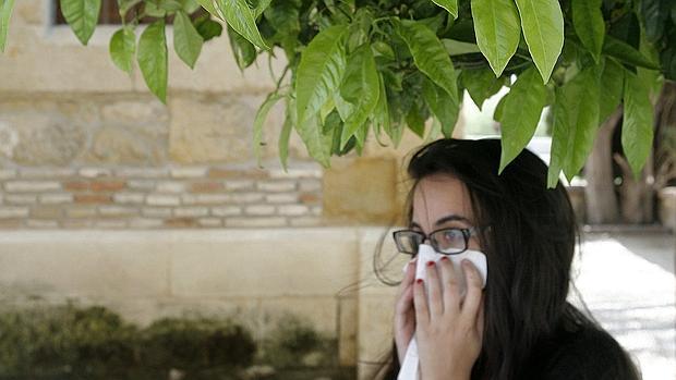 Una joven alérgica estornuda junto a un árbol en Córdoba