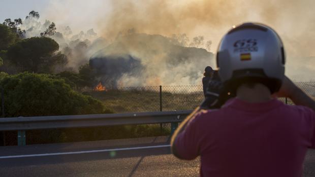 Un motorista roma una imagen del fuego desde la carretera cortada ayer al tráfico