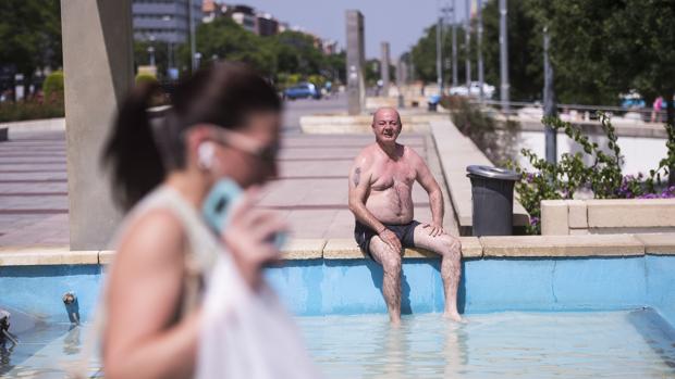 Un hombre se refresca en una de las fuentes de la avenida de la Libertad en Córdoba