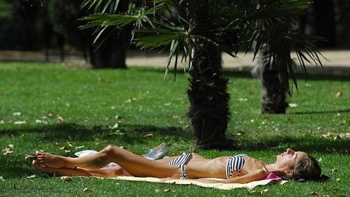 Una chica toma el sol en un parque durante la mañana