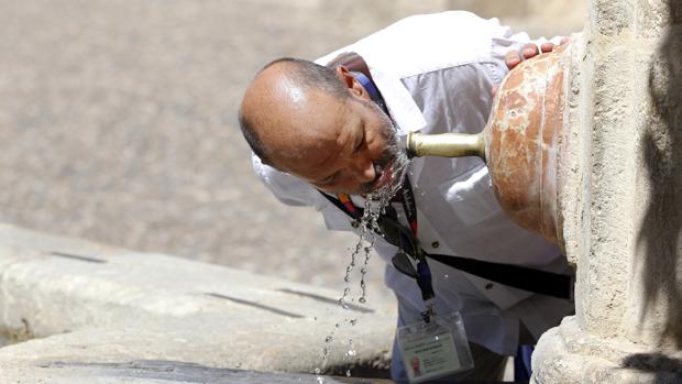 Un turista se refresca del calor cordobés con el agua de una fuente