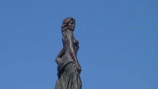 Una mujer corona la columna del Monumento al Turista de Gómez