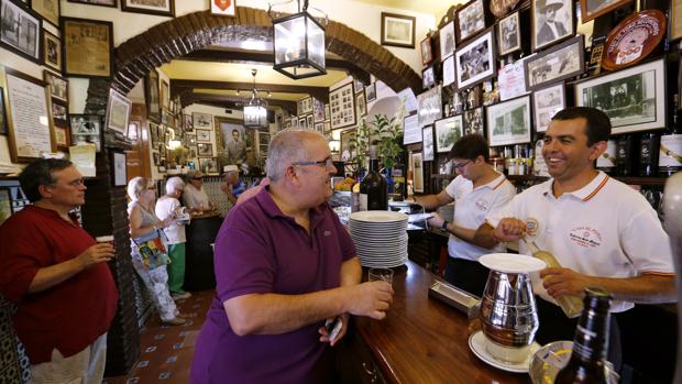 Varias personas toman un vino en una taberna