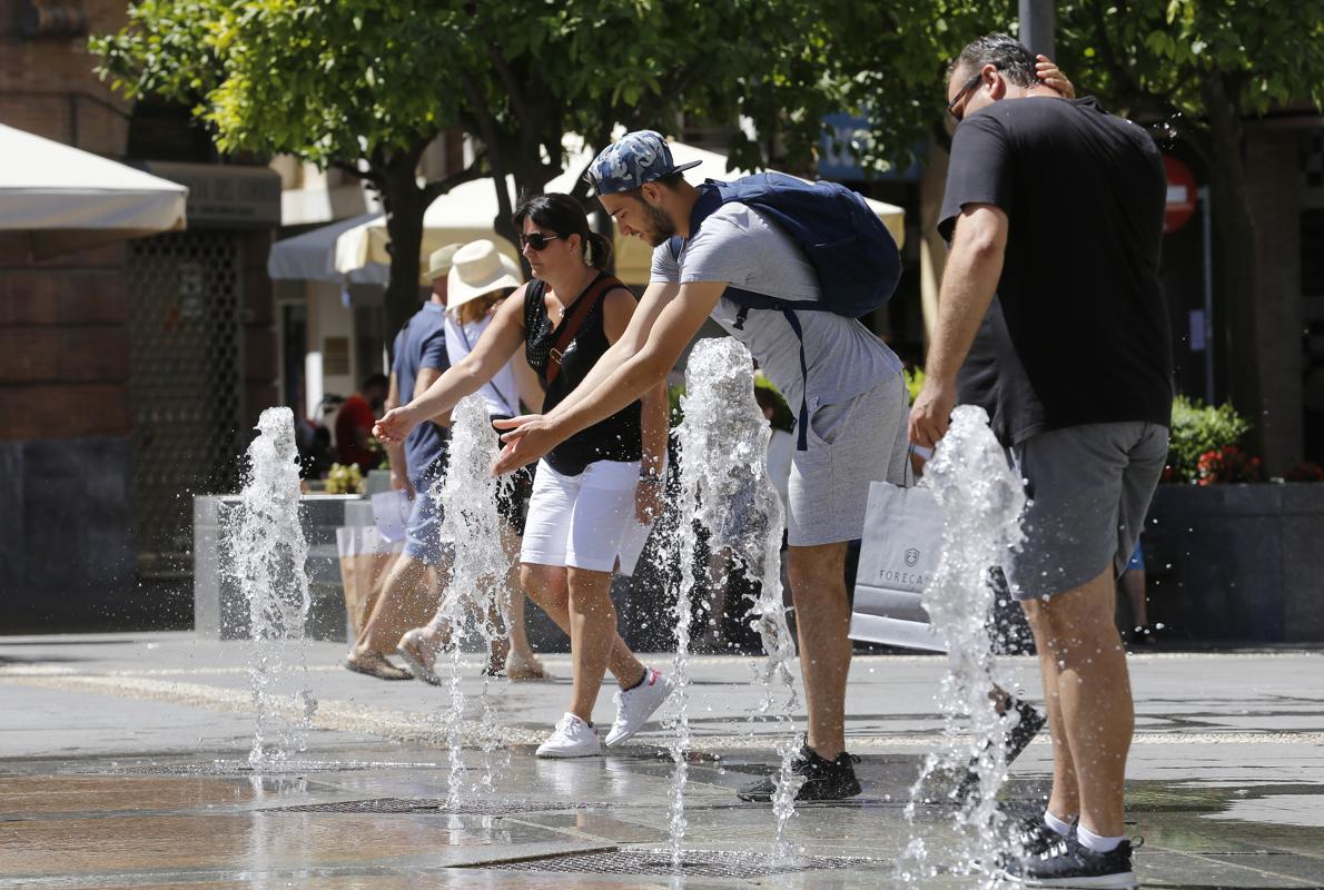 Turistas refrescándose en una fuente