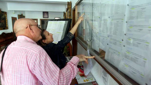 Dos personas consultan las listas de escolarizacion en un centro