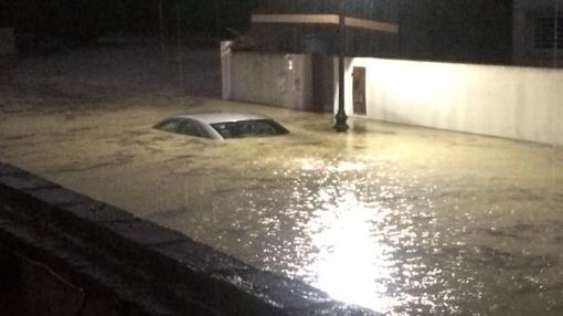 Un coche hundido bajo el agua tras el paso de la tormenta en el término de Aljaraque