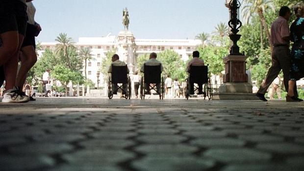 Tres personas en silla de ruedas en la plaza Nueva de Sevilla