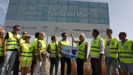 Unaa comitiva del PP, bajo el cartel del hospital que la Junta no construyó