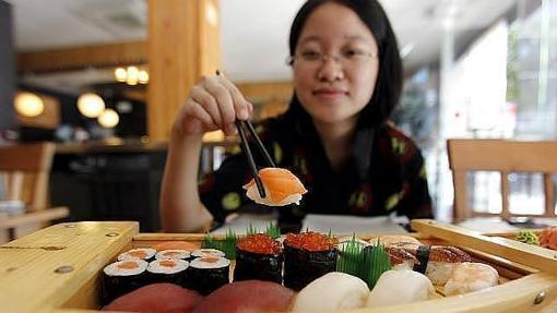 Una cliente se sirve sushi de una bandeja