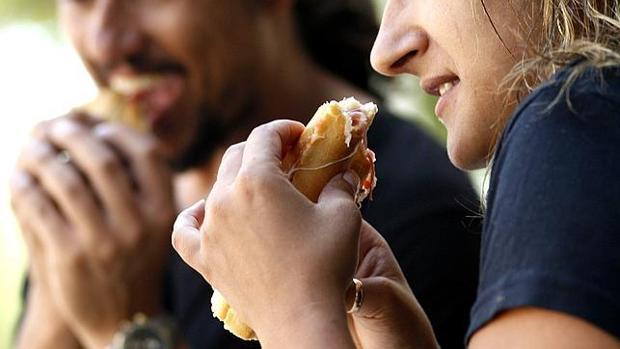 Dos jóvenes comidndo un bocadillo de jamón