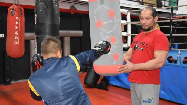 Liberto Toro enseña a Felipe a dar golpes al saco en su gimnasio