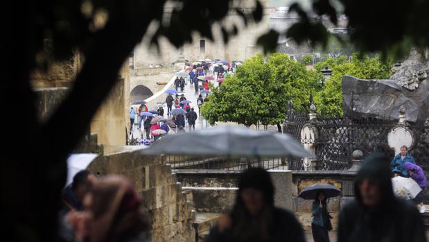 Turistas pasean por el entorno de la Mezquita en un día de lluvia