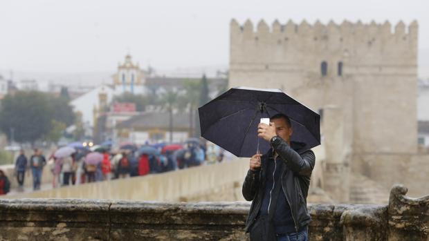 Turistas con paraguas por el Puente Romano de Córdoba