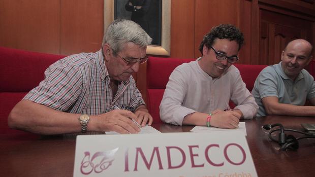 Antonio Rojas, presidente de IMDECO,, firma un acuerdo a la derecha de la imagen