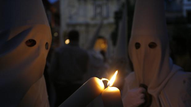 Dos nazarenos encendiendo sus cirios.