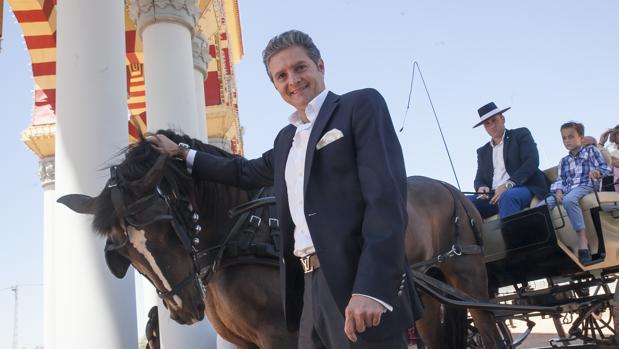 Chiquilín posa sontiente junto a un coche de caballos bajo la portada de la Feria