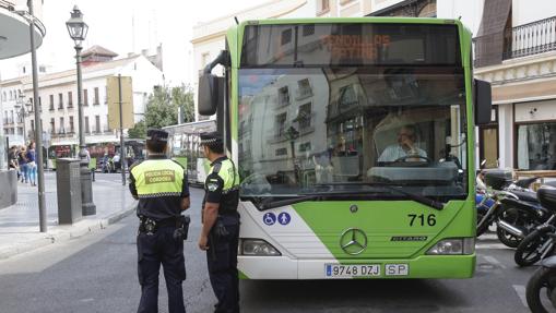 Dos agentes de la Policía Local junto a un autobús averiado