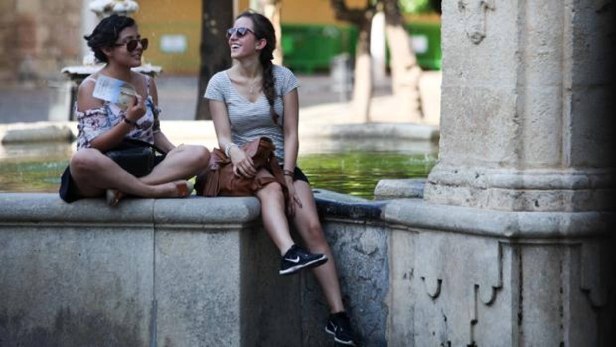 Dos turistas descansan en el Patio de los Naranjos durante la pasada ola de calor en junio