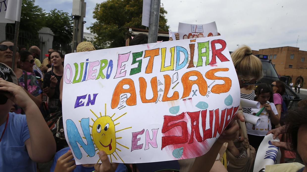 Un niño alza una pancarta en una manifestación por el calor en las aulas frente al Parlamento andaluz