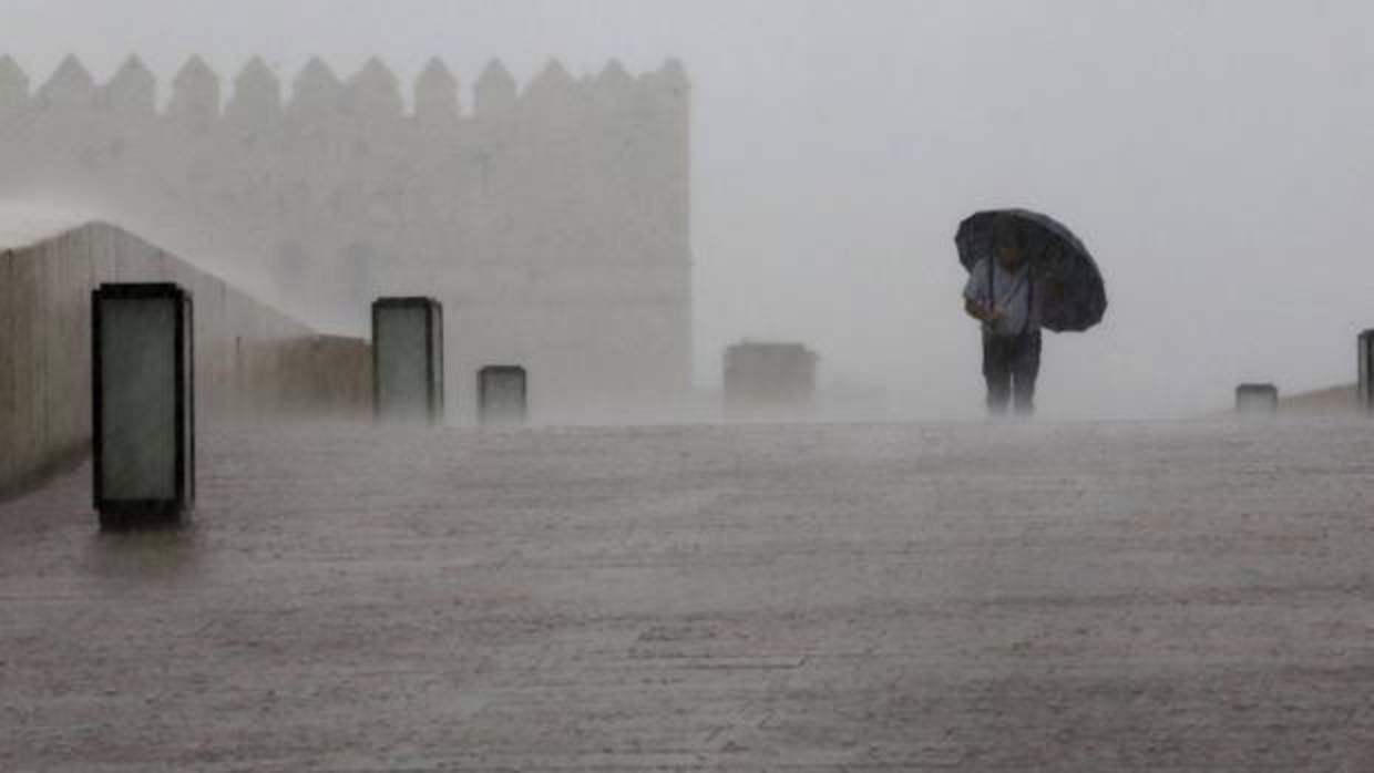 Un hombre cruza el Puente Romano en plena tormenta en Córdoba