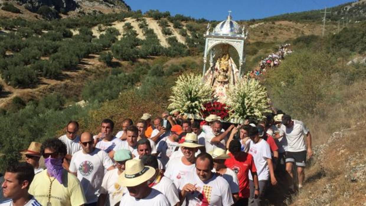 Costaleros y romeros portan las andas de la Virgen de la Sierra por el camino montañoso