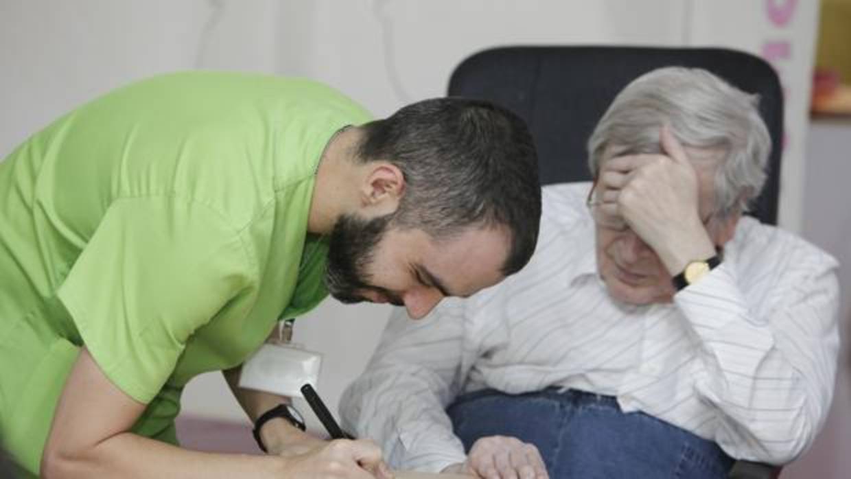 Un hombre aquejado de la enfermedad junto a un trabajador de la Asociación de Alzheimer