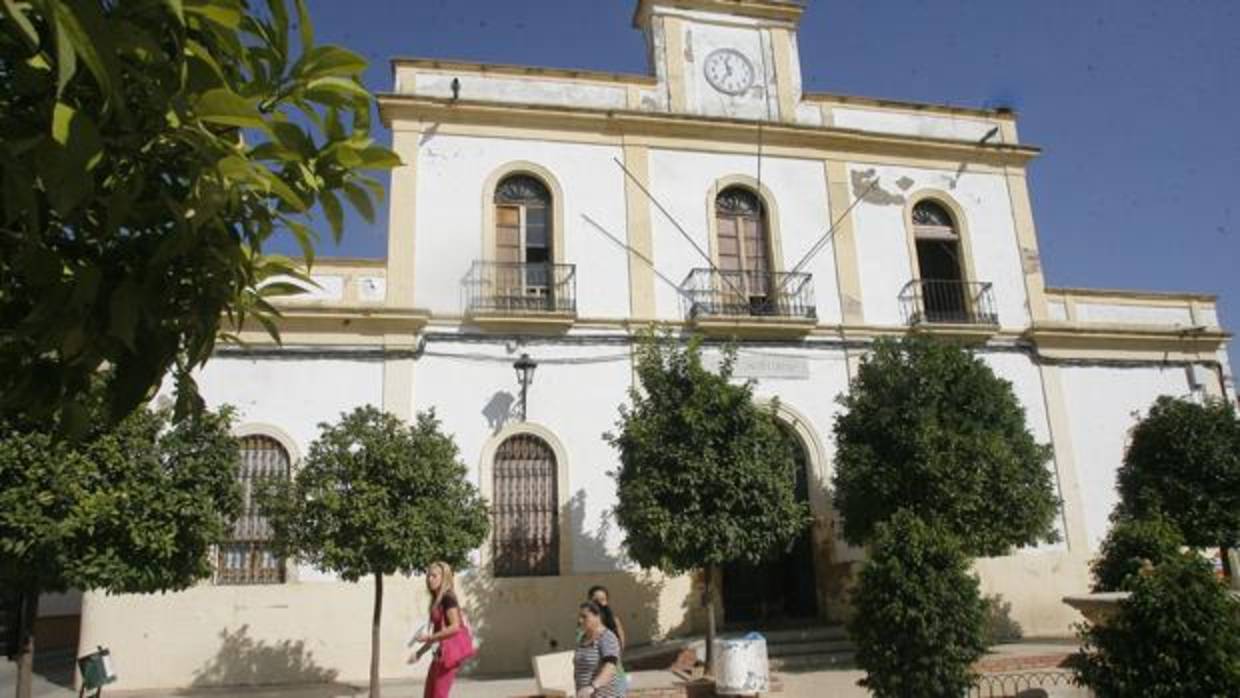 Tres mujeres pasan por delante de la fachada del Ayuntamiento maleno