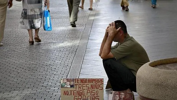 Un hombre pide limosna en una calle de Sevilla